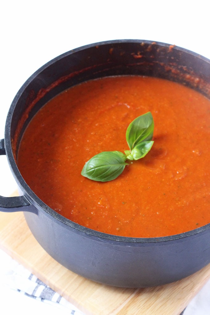 A large pot of hidden veggie tomato sauce garnished with fresh basil leaves.