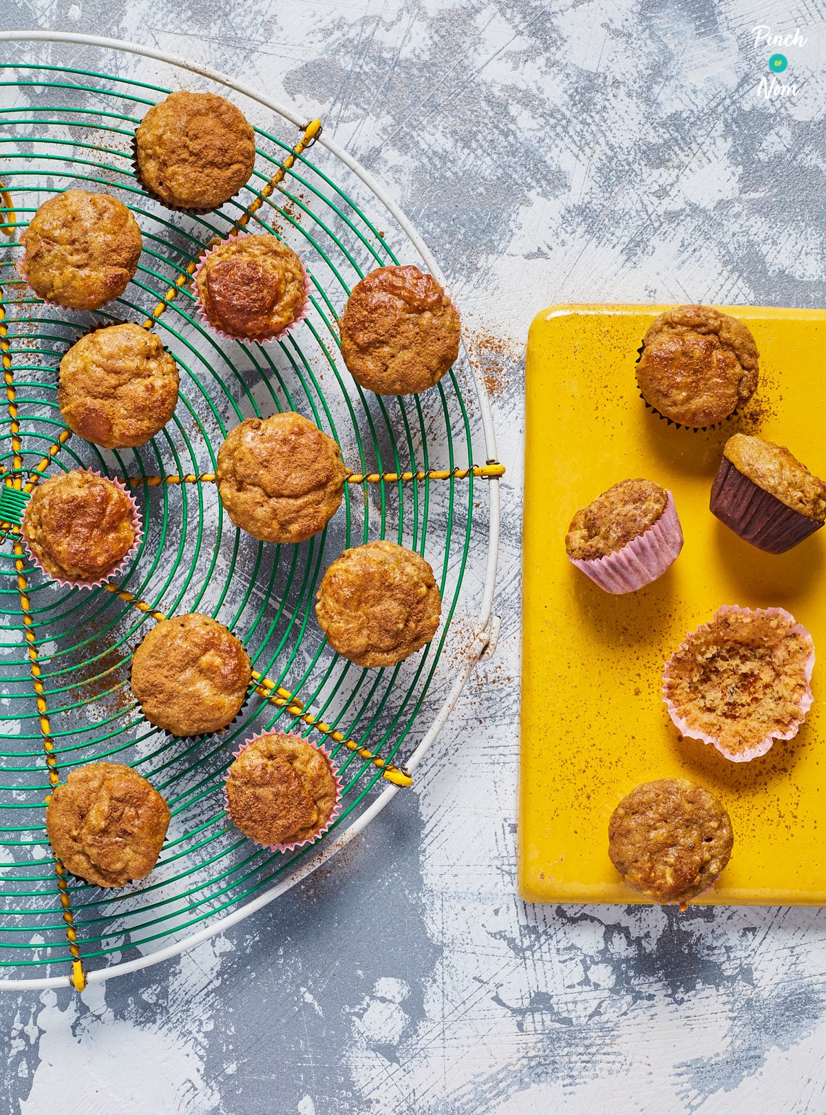 Pinch of Nom's Banana and Peanut Muffins are served on a wire rack looking fluffy and golden – a cupcake case is empty where one has already been eaten!