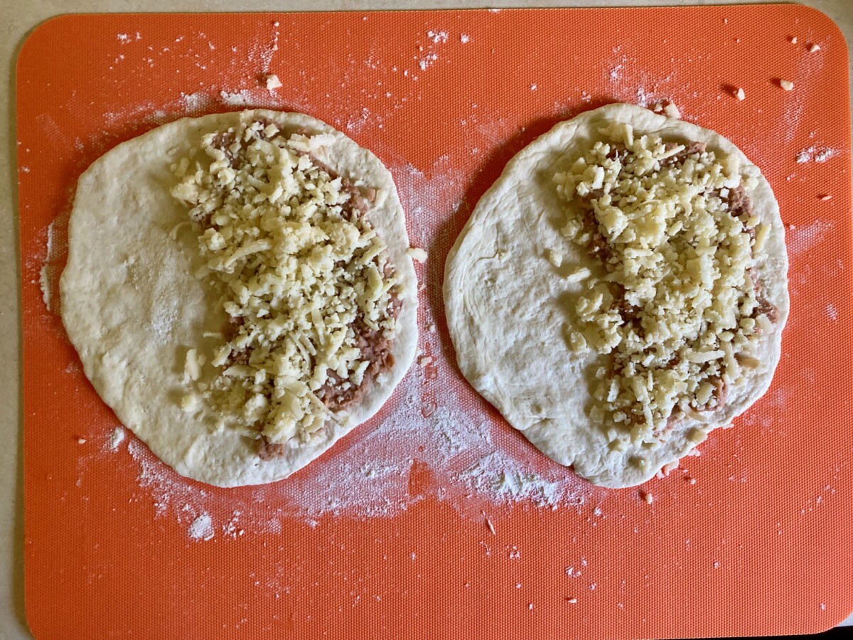 Refried beans and shredded cheese on 2-ingredient dough.
